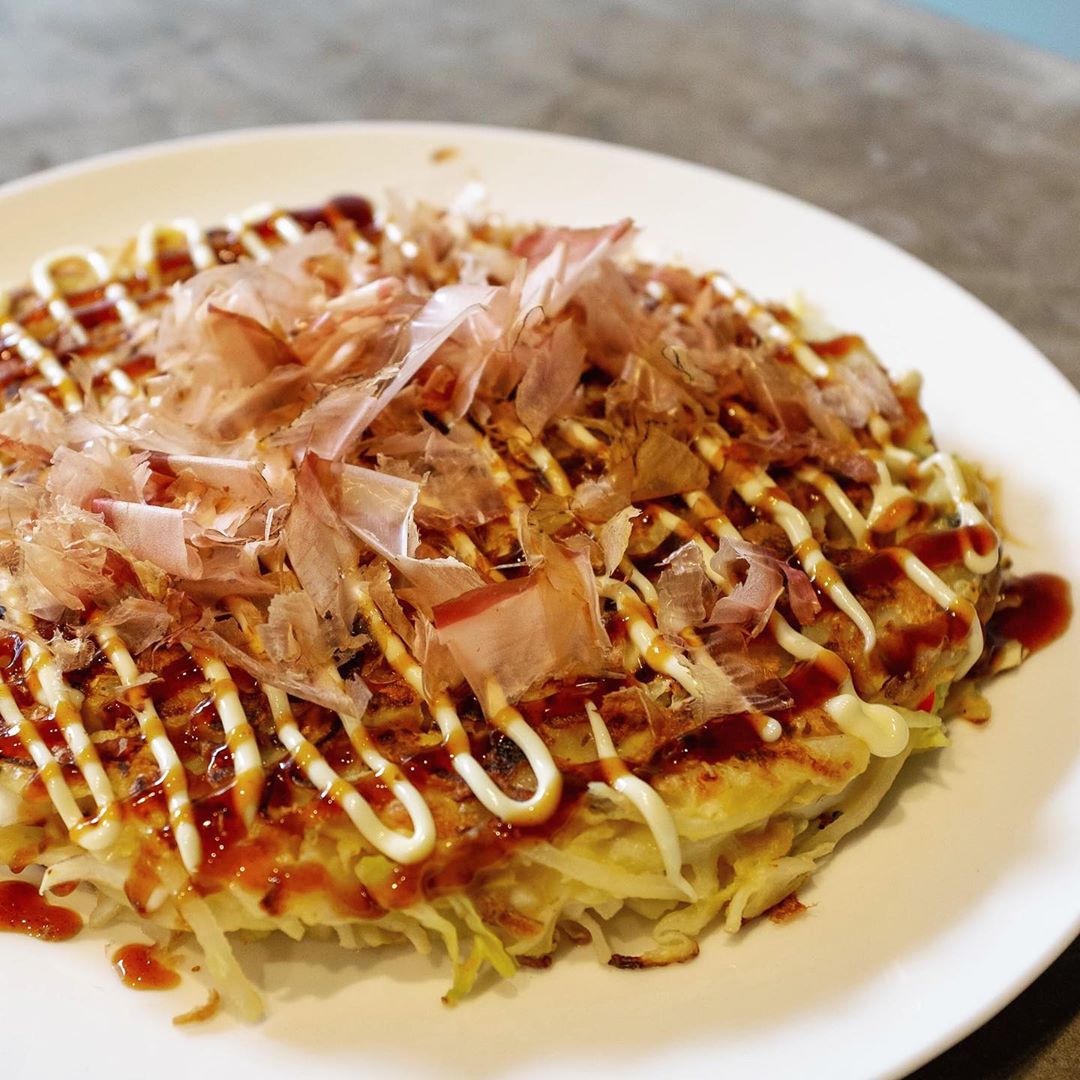OK okonomiyaki fans, here is the recipe I used for today’s okonomiyaki pancake. The recipe varies depending on what I have around… I wouldn’t normally use onion but I have a lot right now so in it goes!

Ingredients:
* 200g cabbage
* 70g onion (half a small one)
* 5mm slice of ginger
* 75g flour
* 100ml water
* 1 egg
* A whole chilli
* A big spoonful of fried shallots
* Mysterious rice seasoning
* Vegetable oil (canola, peanut, etc)

To serve:
* Kewpie mayonnaise
* Otafuku okonomi sauce
* Shaved bonito

Start by chopping the vegetables finely. If the cabbage is chopped too coarse I find it doesn’t cook, so chop thin slices. 
In a mixing bowl add the flour and water (but not the egg), then mix it into a paste. I have a mysterious pack of Japanese rice seasoning so I added a spoonful here. Then mix in all the vegetables and fried shallots into the paste. Give it a good stir to make sure everything is coated. Then break an egg on top and mix it through.

Heat a frypan to a medium-high heat, with a little oil. My induction cooktop has heat levels 1 to 9, I use 7 for this. Spoon the mixture into the pan then flatten it out into a thick pancake shape. Cook for 6-7 minutes on one side, then flip over. Cook another 6-7 minutes on the other side.

Now the fun saucy part! Slide the okonomiyaki onto a plate. Squeeze some mayonnaise in lines across the whole pancake. Squeeze some okonomi sauce in lines in the other direction. Now throw a small handful of shaved bonito on top. Eat!